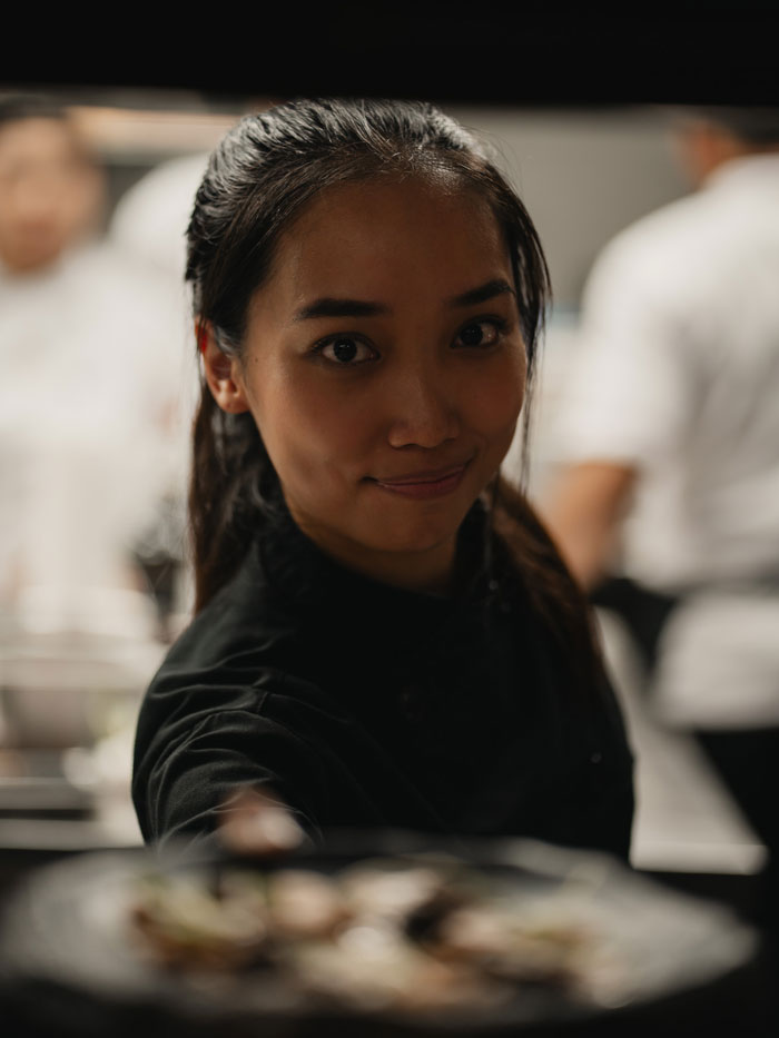 Smiling chef at Kaban Bali restaurant in Umalas, preparing fresh fusion cuisine in the open kitchen